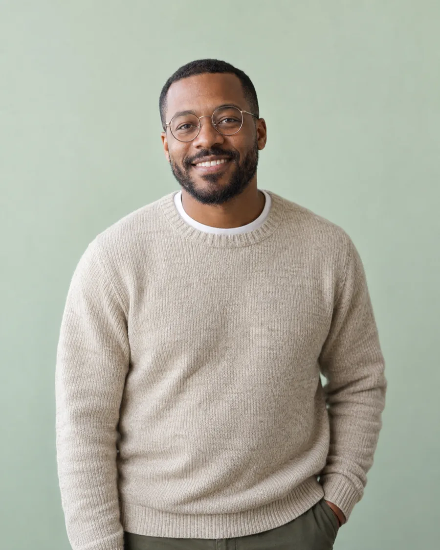 Marcus Bell, clinical social worker, smiling in round glasses and an oatmeal sweater