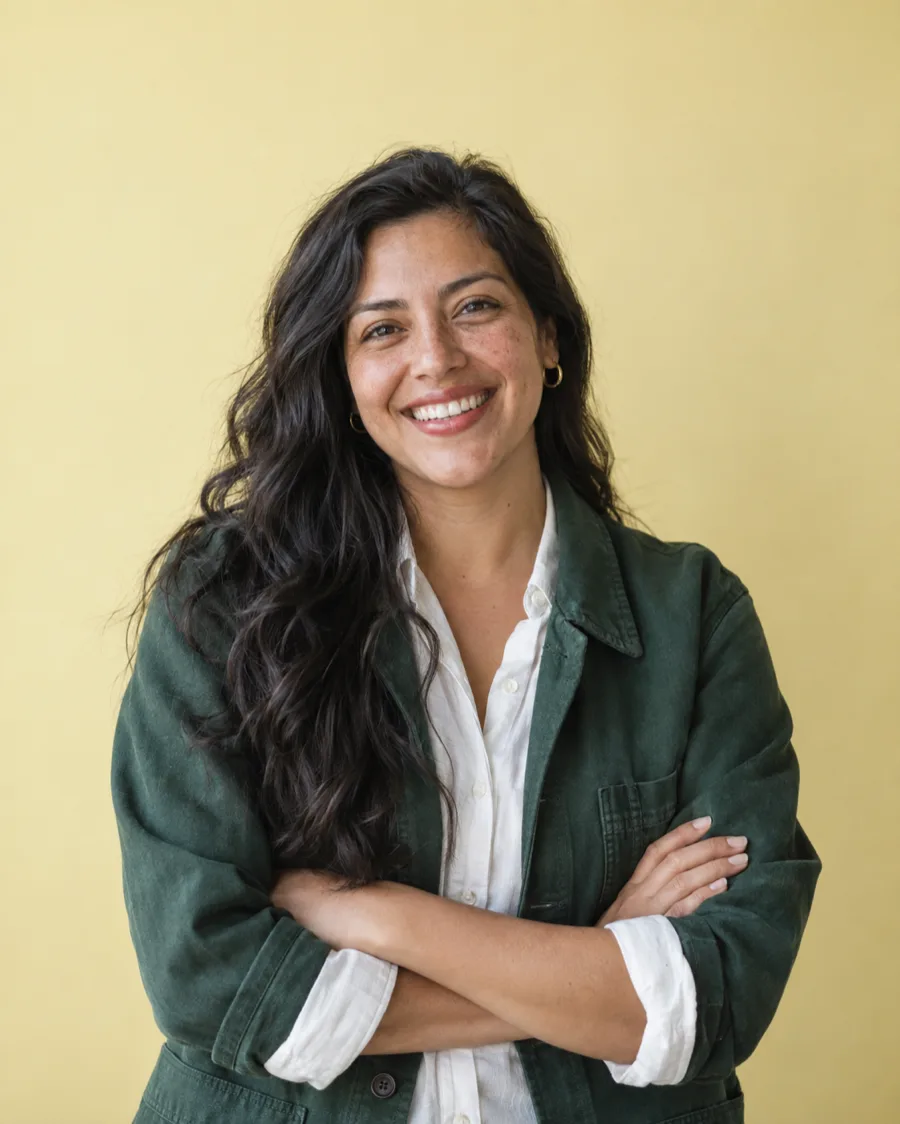 Elena Vasquez standing against a butter yellow backdrop, laughing